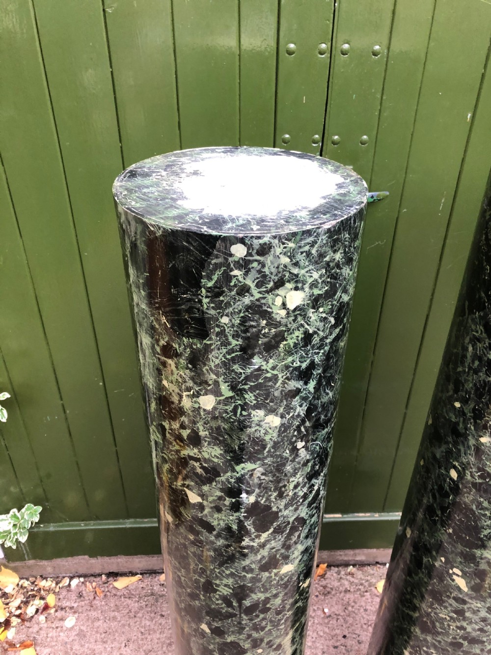 A pair of tall mid-19th century cylindrical wooden display columns painted in a green and black faux verde antico marble finish with square bases. View VI