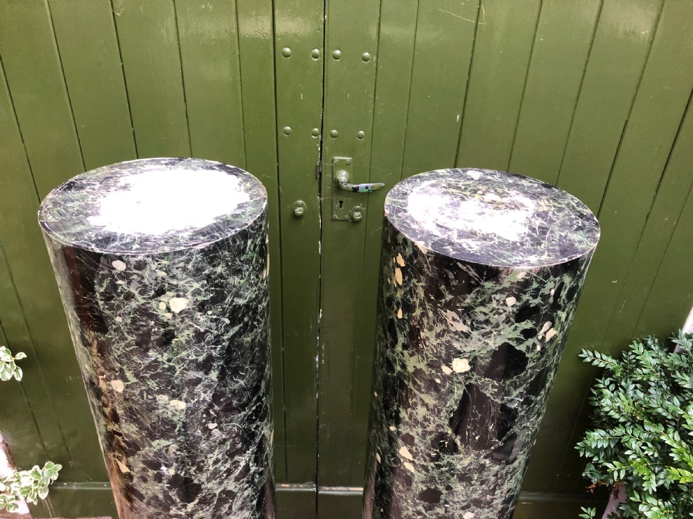 A pair of tall mid-19th century cylindrical wooden display columns painted in a green and black faux verde antico marble finish with square bases. View VII