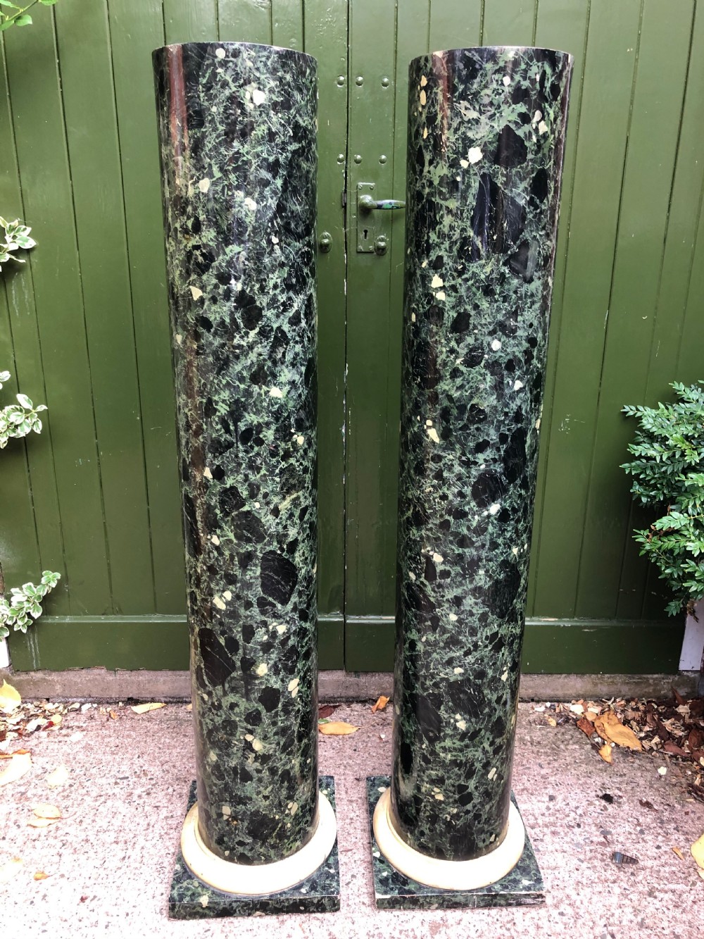 A pair of tall mid-19th century cylindrical wooden display columns painted in a green and black faux verde antico marble finish with square bases. View XI