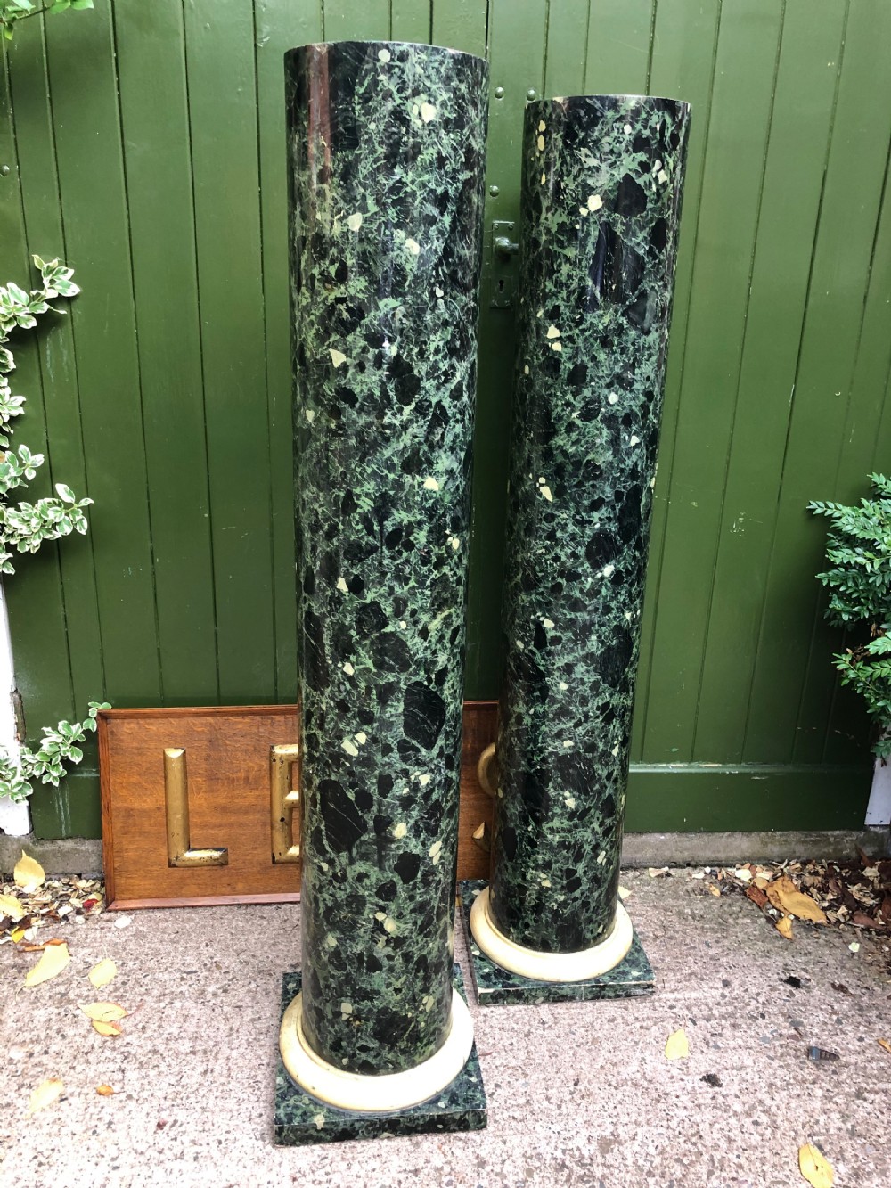 A pair of tall mid-19th century cylindrical wooden display columns painted in a green and black faux verde antico marble finish with square bases. View XII