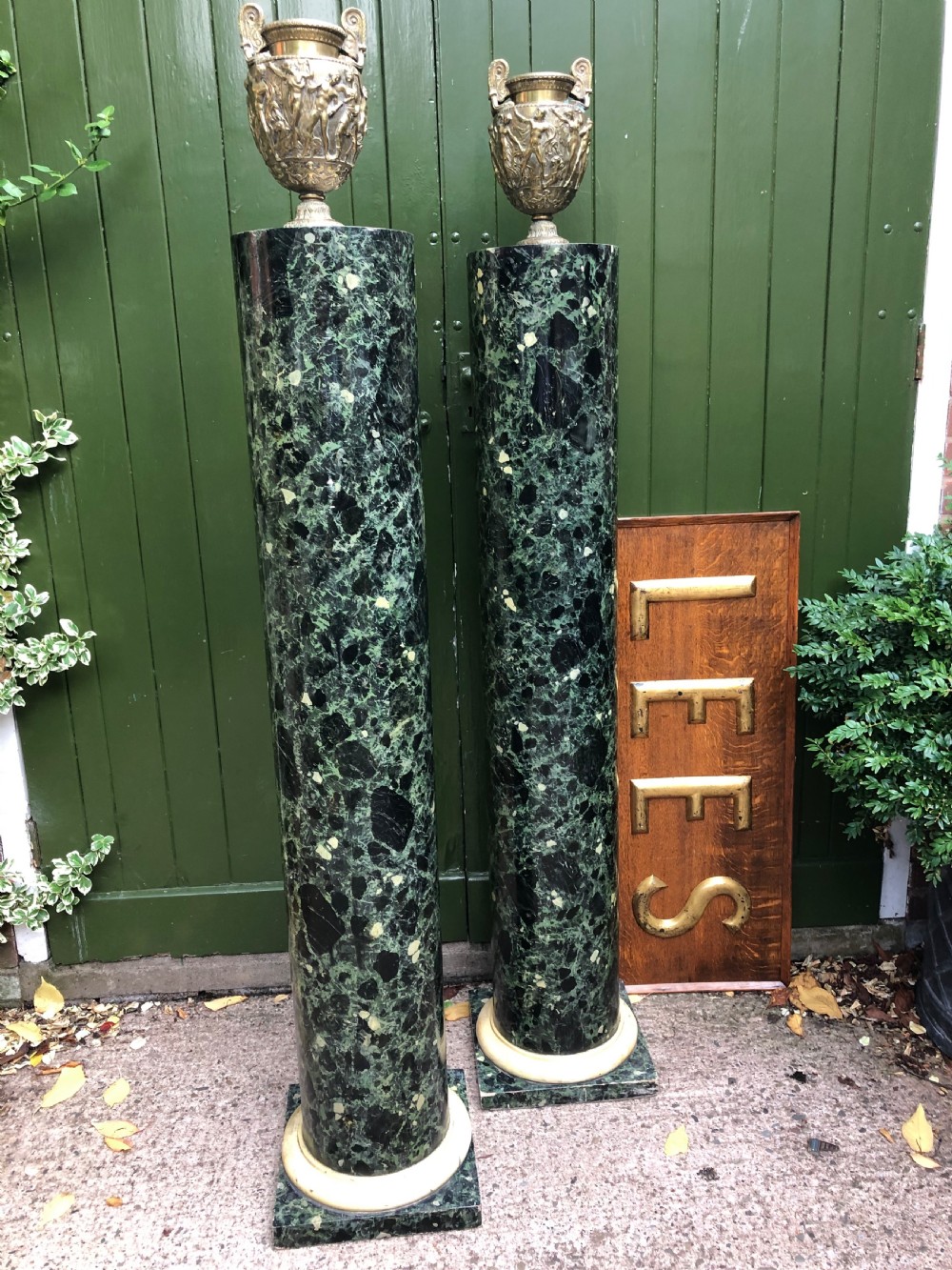 A pair of tall mid-19th century cylindrical wooden display columns painted in a green and black faux verde antico marble finish with square bases. View XVI