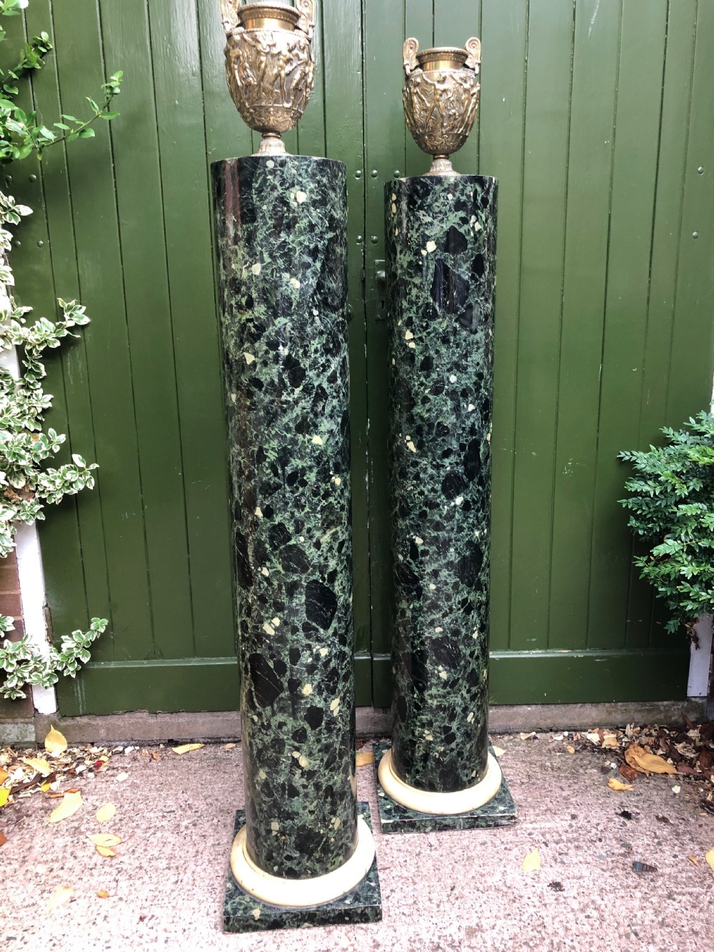 A pair of tall mid-19th century cylindrical wooden display columns painted in a green and black faux verde antico marble finish with square bases. View XVII