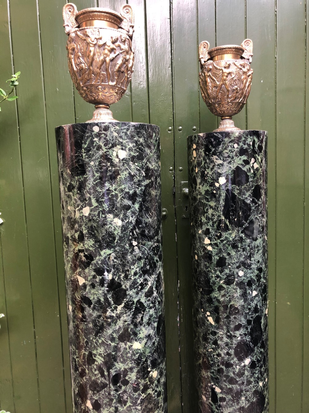 A pair of tall mid-19th century cylindrical wooden display columns painted in a green and black faux verde antico marble finish with square bases. View XVIII