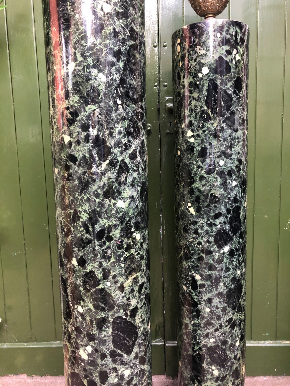 A pair of tall mid-19th century cylindrical wooden display columns painted in a green and black faux verde antico marble finish with square bases. View XIX