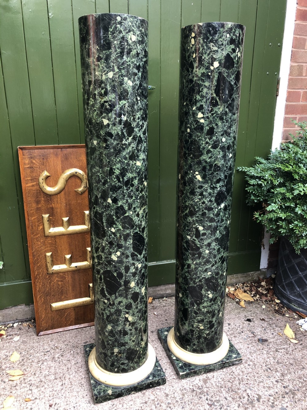 A pair of tall mid-19th century cylindrical wooden display columns painted in a green and black faux verde antico marble finish with square bases. View XXIII