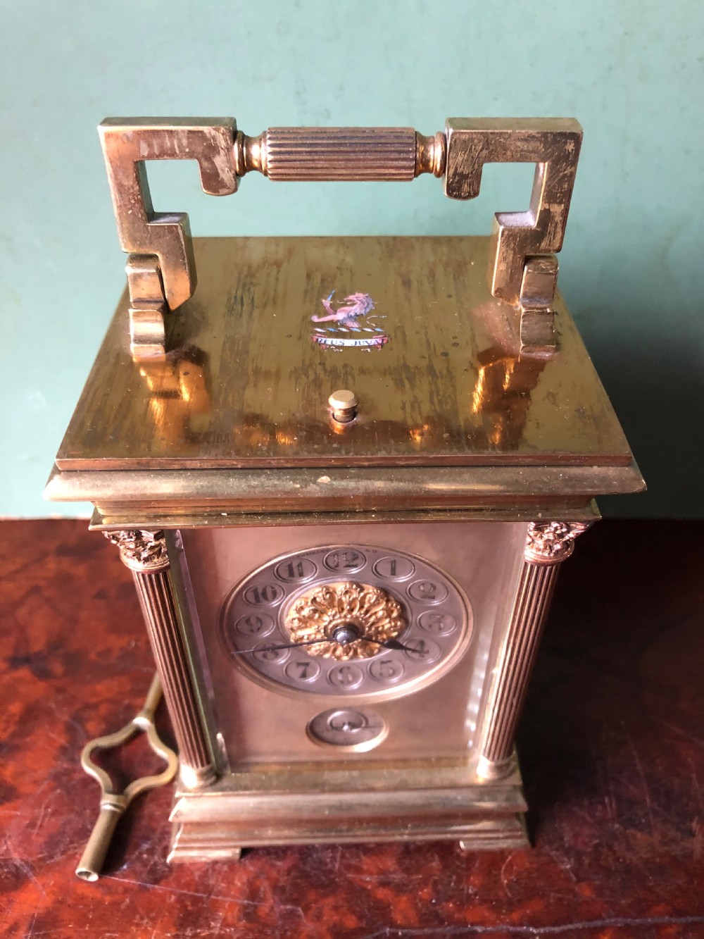 A late nineteenth-century French gilt brass carriage clock featuring fluted Corinthian corner columns, a carrying handle, a central dial with Arabic numerals, a lower subsidiary dial, and an adjacent winding key. View II