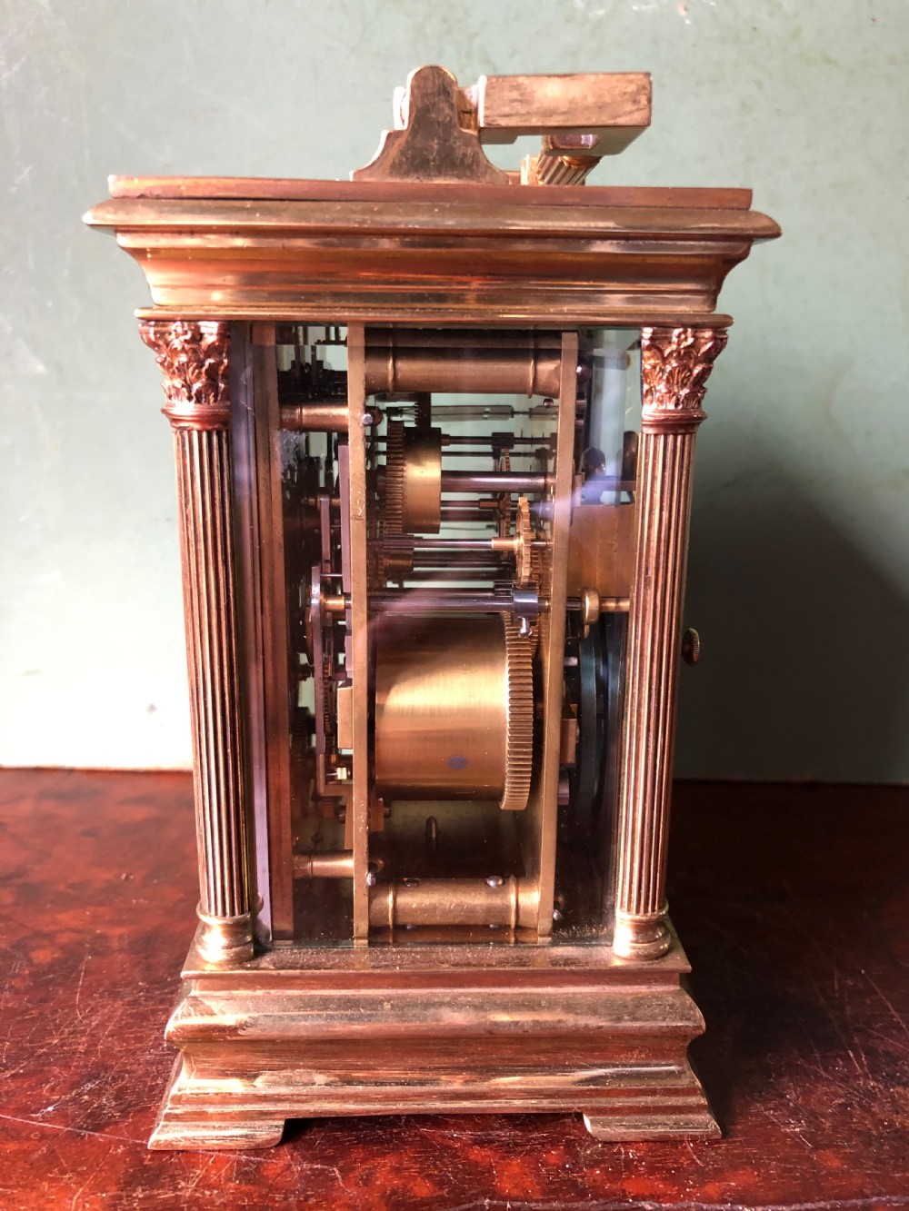 A late nineteenth-century French gilt brass carriage clock featuring fluted Corinthian corner columns, a carrying handle, a central dial with Arabic numerals, a lower subsidiary dial, and an adjacent winding key. View VI