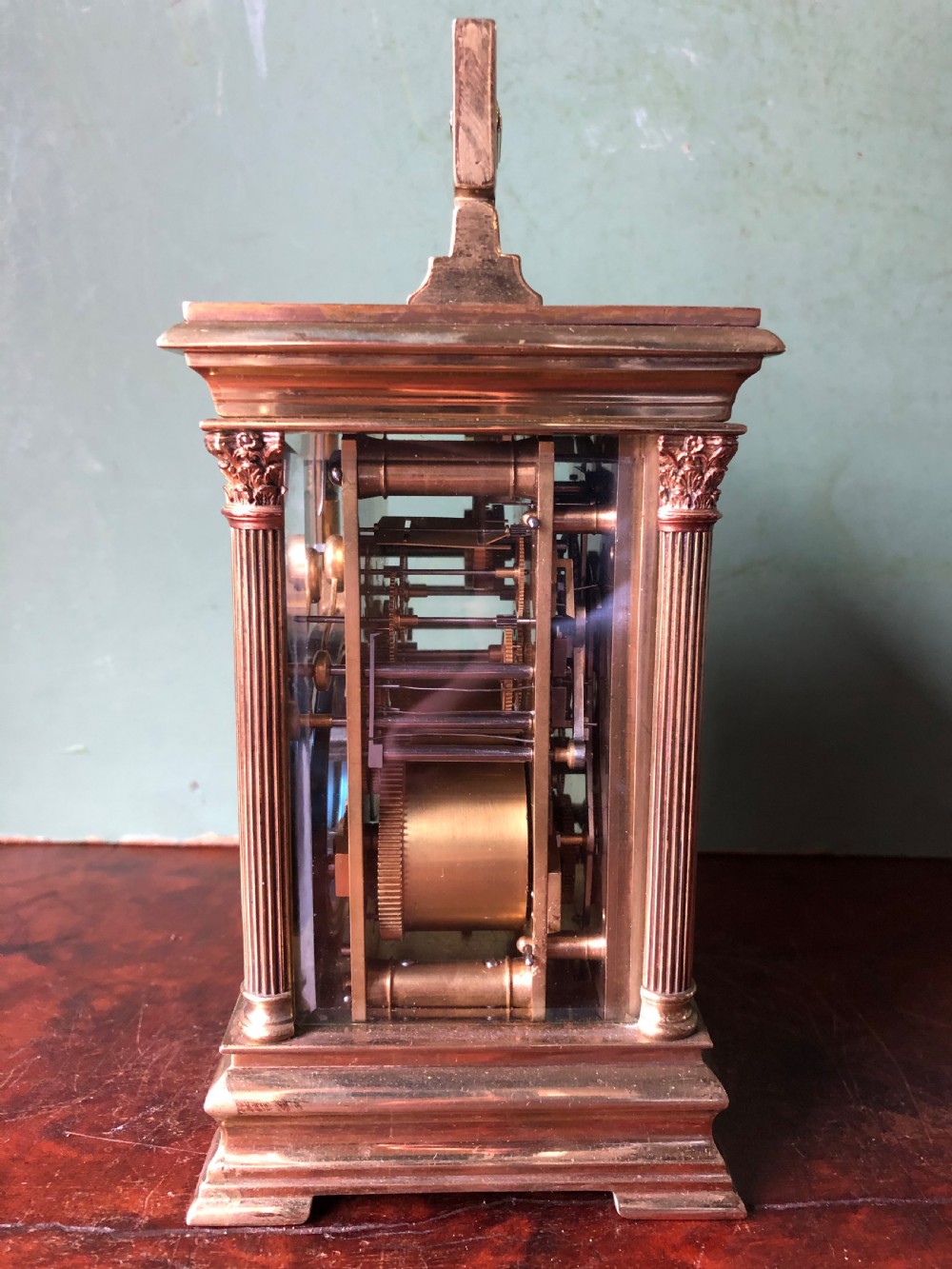 A late nineteenth-century French gilt brass carriage clock featuring fluted Corinthian corner columns, a carrying handle, a central dial with Arabic numerals, a lower subsidiary dial, and an adjacent winding key. View IX