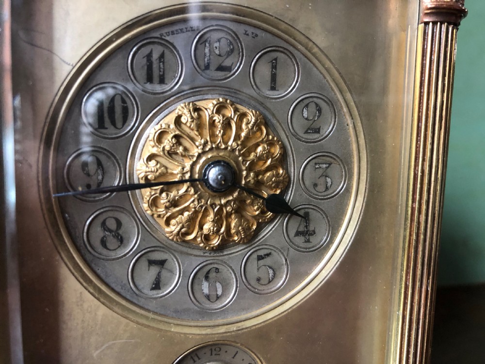 A late nineteenth-century French gilt brass carriage clock featuring fluted Corinthian corner columns, a carrying handle, a central dial with Arabic numerals, a lower subsidiary dial, and an adjacent winding key. View XIII
