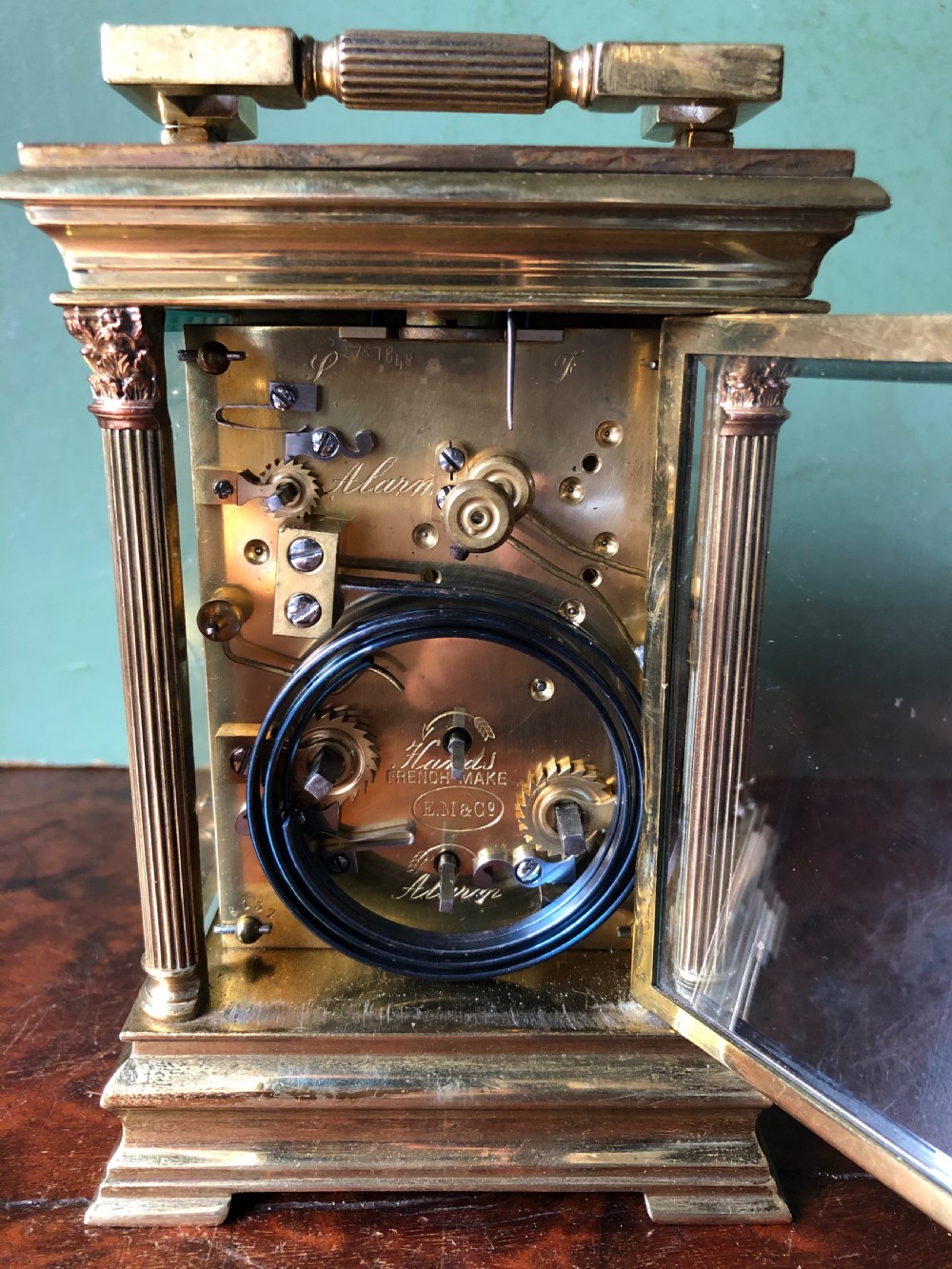 A late nineteenth-century French gilt brass carriage clock featuring fluted Corinthian corner columns, a carrying handle, a central dial with Arabic numerals, a lower subsidiary dial, and an adjacent winding key. View XIV