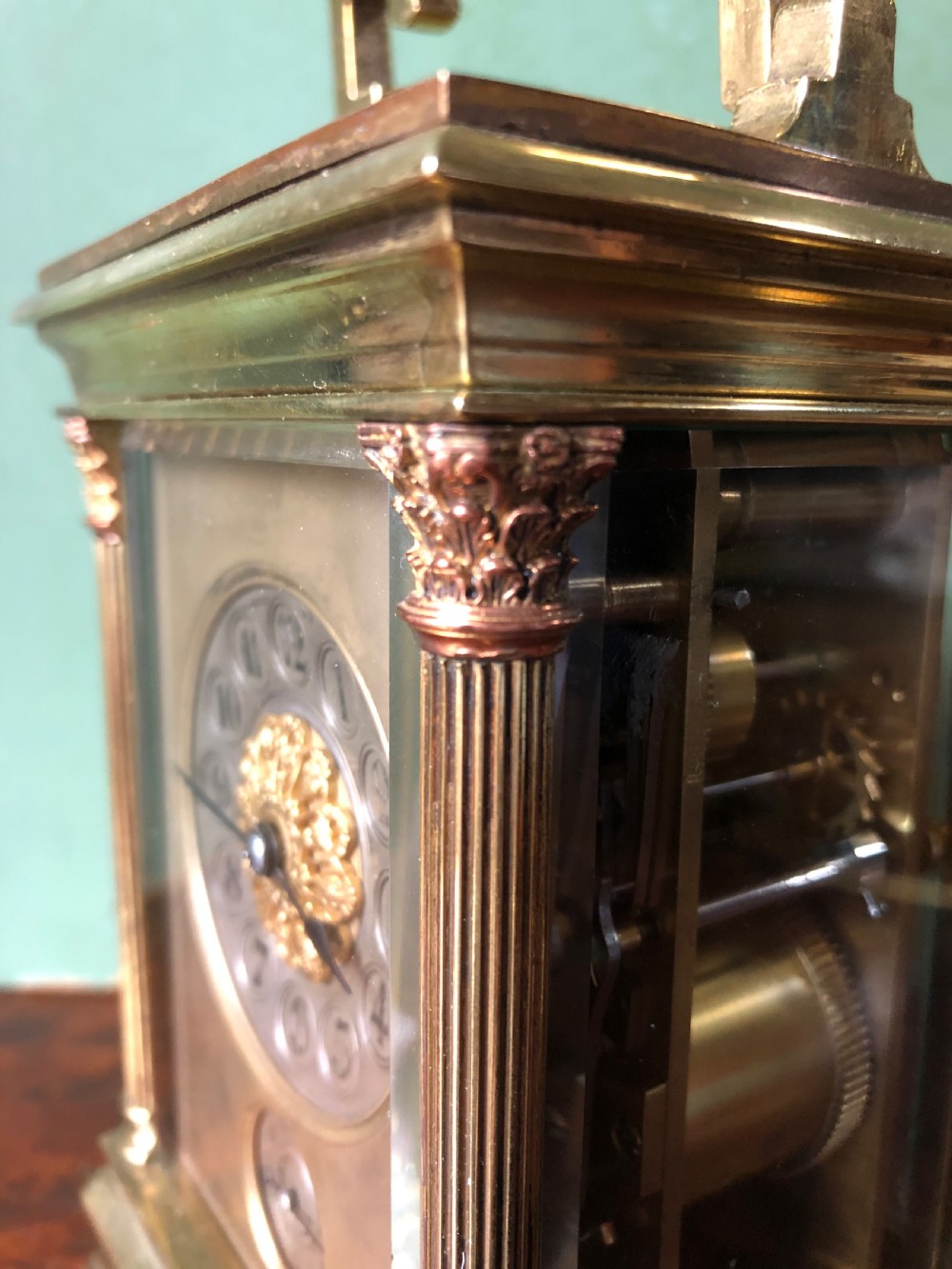 A late nineteenth-century French gilt brass carriage clock featuring fluted Corinthian corner columns, a carrying handle, a central dial with Arabic numerals, a lower subsidiary dial, and an adjacent winding key. View XXI