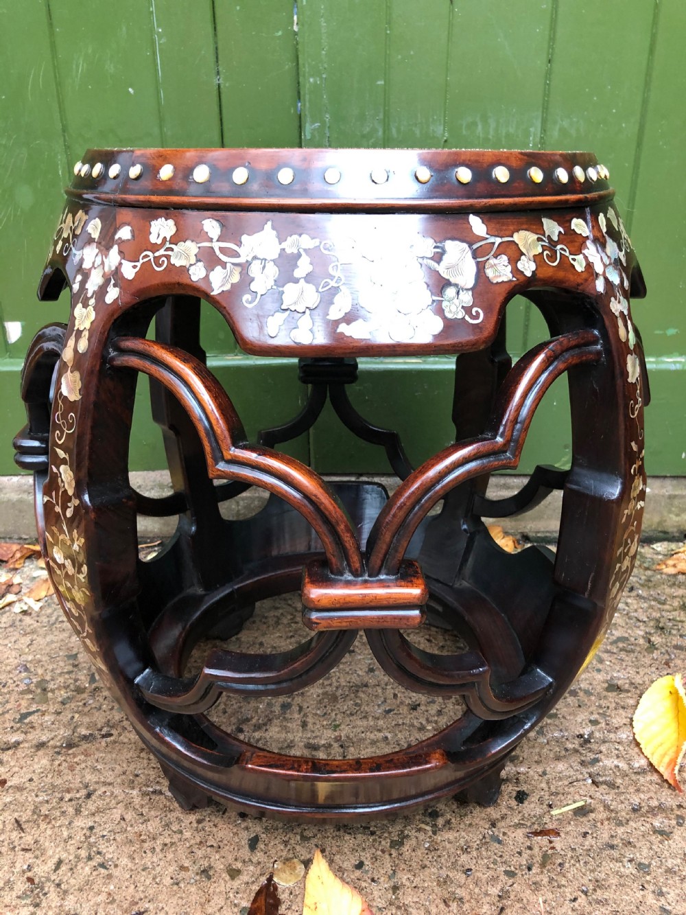 A nineteenth-century Chinese dark hongmu drum-shaped stool decorated with mother-of-pearl floral inlay and carved openwork sides.