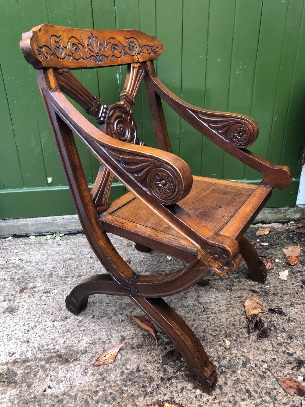 A nineteenth-century carved oak armchair featuring an X-frame back with a central rosette, scrolled armrests, and curved legs. View VII