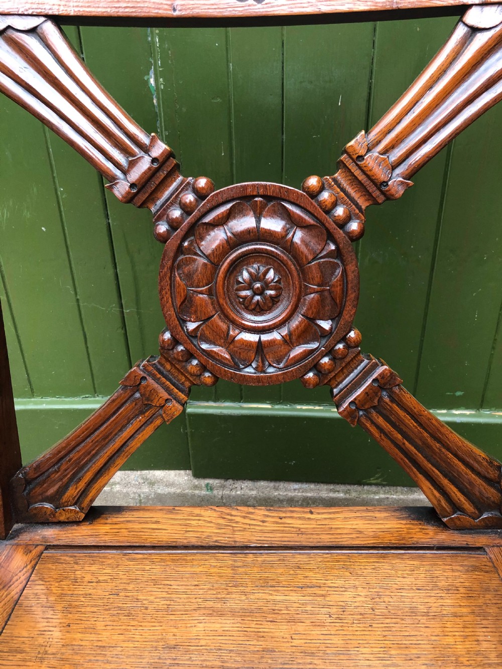 A nineteenth-century carved oak armchair featuring an X-frame back with a central rosette, scrolled armrests, and curved legs. View VIII
