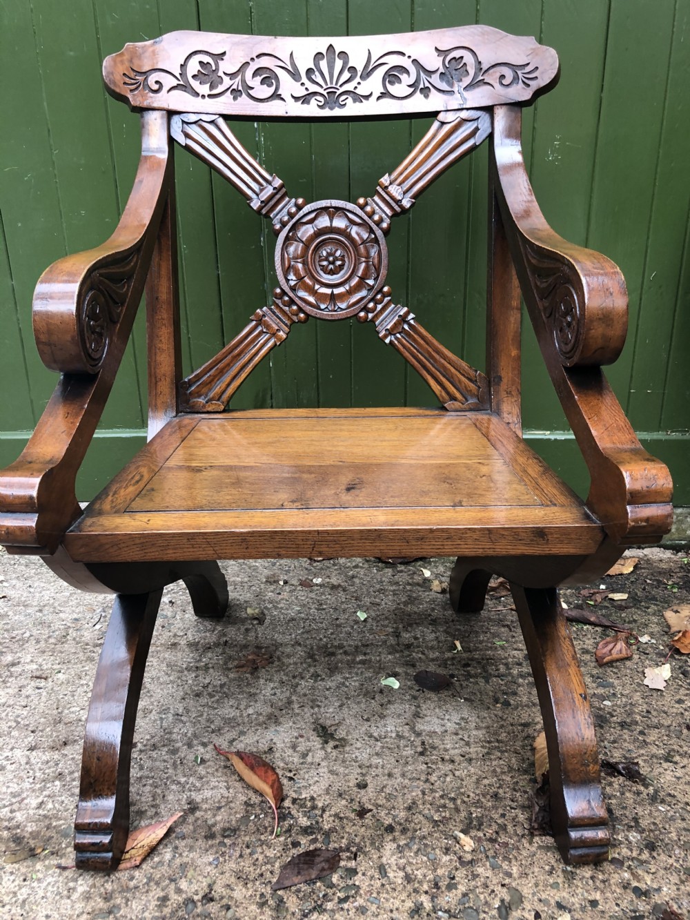 A nineteenth-century carved oak armchair featuring an X-frame back with a central rosette, scrolled armrests, and curved legs. View XI