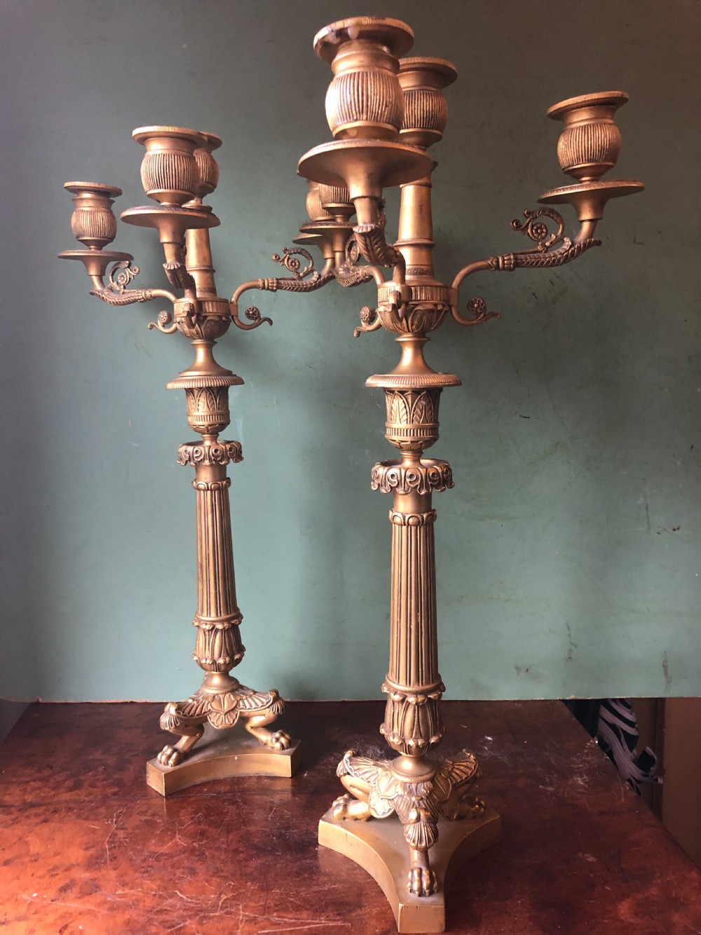 A pair of early nineteenth-century French Charles X gilt bronze candelabras featuring fluted columns, ornate scrolled arms, and decorative leaf motifs. View II
