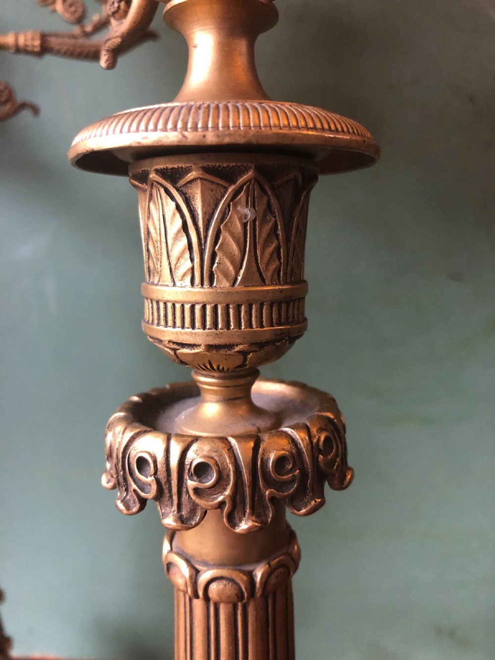 A pair of early nineteenth-century French Charles X gilt bronze candelabras featuring fluted columns, ornate scrolled arms, and decorative leaf motifs. View V