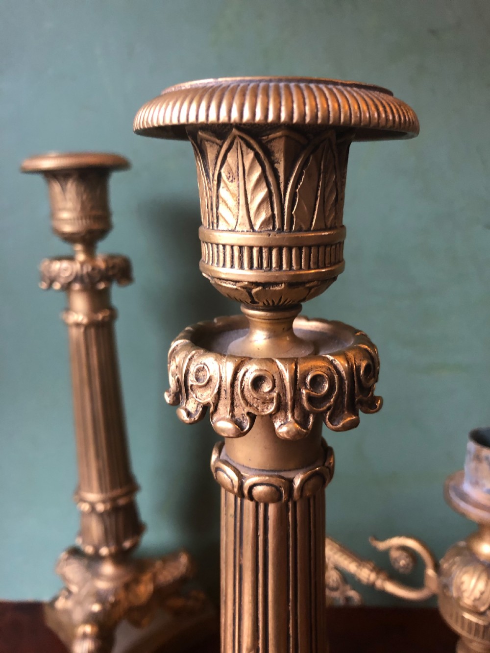 A pair of early nineteenth-century French Charles X gilt bronze candelabras featuring fluted columns, ornate scrolled arms, and decorative leaf motifs. View XV