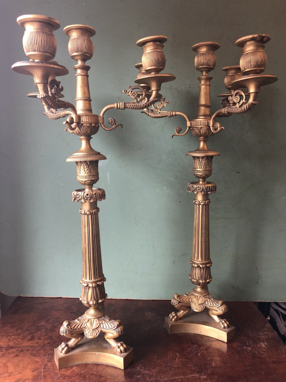 A pair of early nineteenth-century French Charles X gilt bronze candelabras featuring fluted columns, ornate scrolled arms, and decorative leaf motifs. View XXI