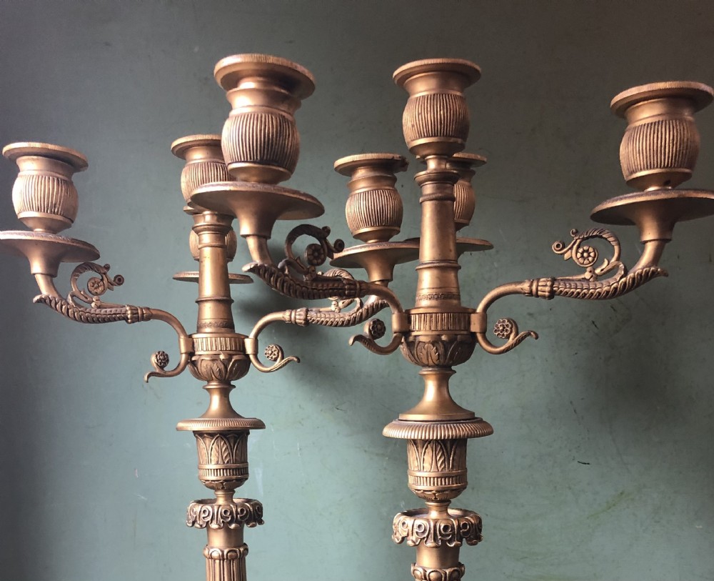 A pair of early nineteenth-century French Charles X gilt bronze candelabras featuring fluted columns, ornate scrolled arms, and decorative leaf motifs. View XXIV