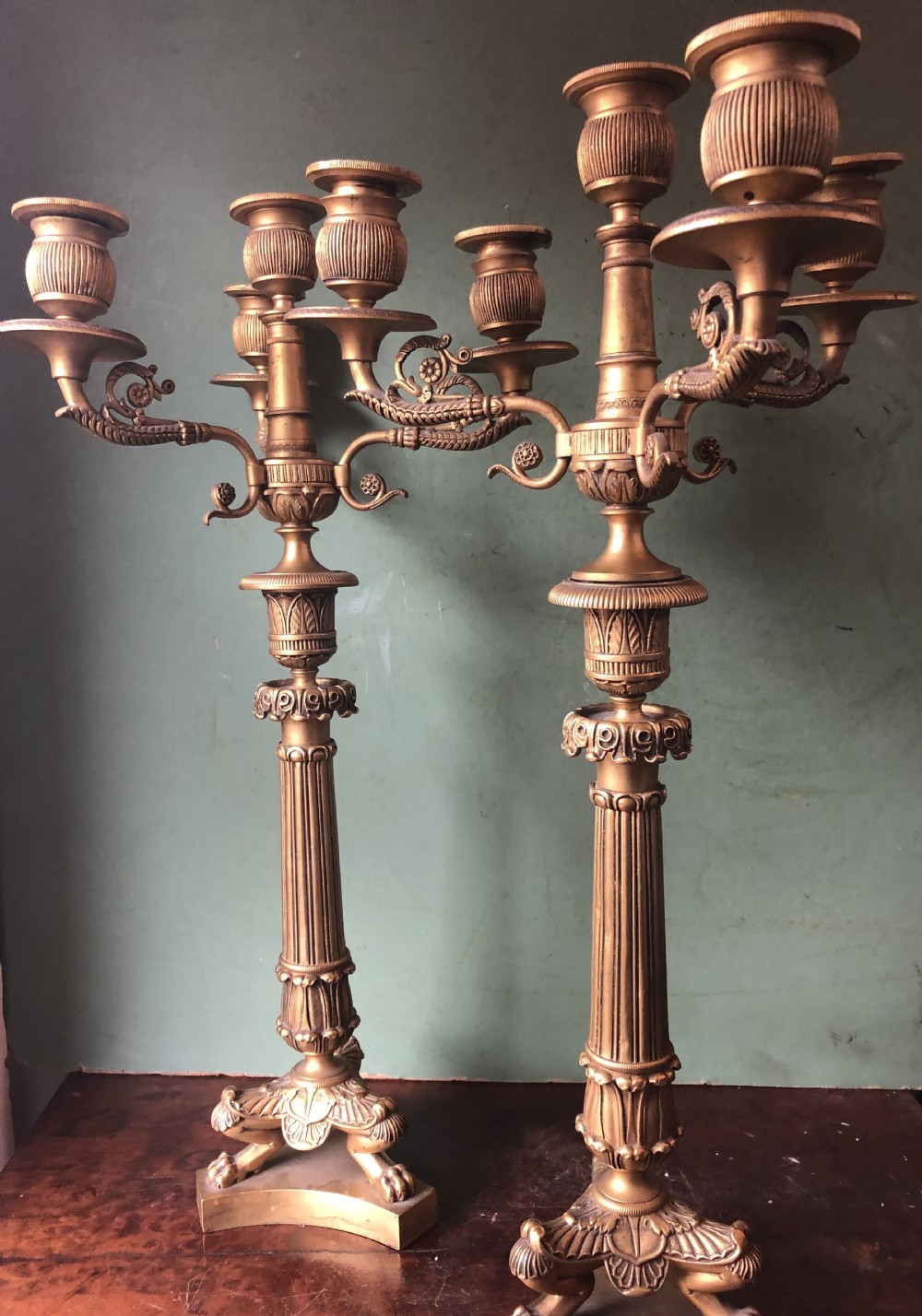 A pair of early nineteenth-century French Charles X gilt bronze candelabras featuring fluted columns, ornate scrolled arms, and decorative leaf motifs.