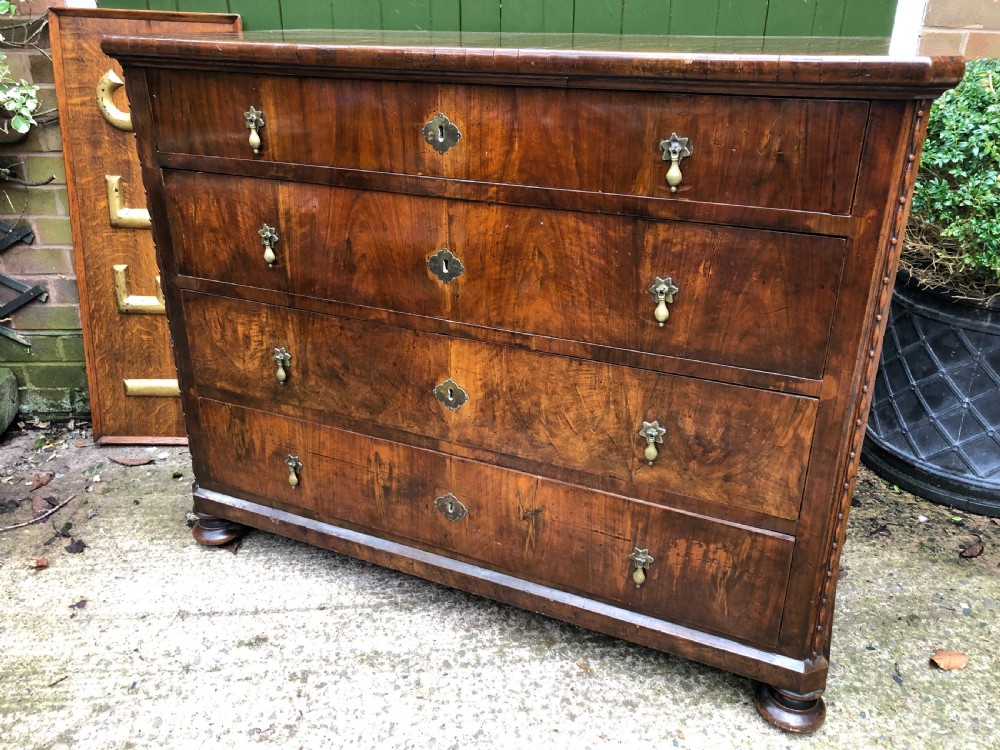 A late eighteenth-century Continental walnut commode chest featuring four long drawers with brass handles and brass escutcheons.