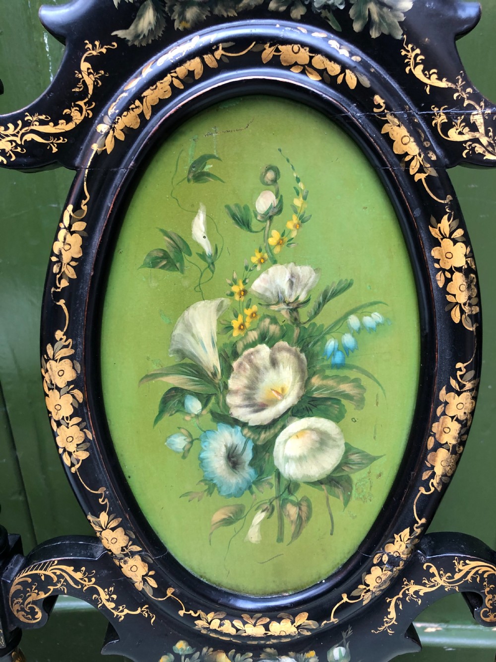 A pair of black lacquered Victorian bedroom chairs featuring oval back panels painted with floral motifs, mother-of-pearl inlay, barley twist legs, and light green upholstered seats. View V