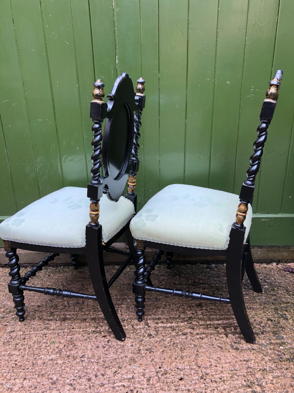 A pair of black lacquered Victorian bedroom chairs featuring oval back panels painted with floral motifs, mother-of-pearl inlay, barley twist legs, and light green upholstered seats. View IX