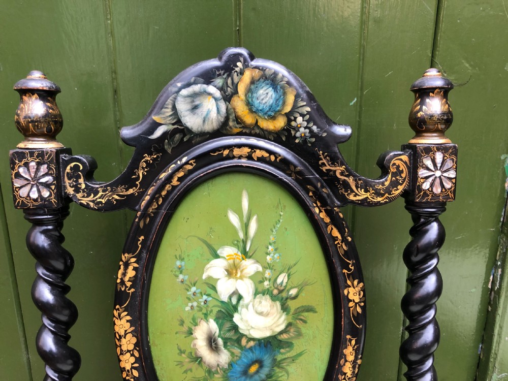 A pair of black lacquered Victorian bedroom chairs featuring oval back panels painted with floral motifs, mother-of-pearl inlay, barley twist legs, and light green upholstered seats. View X