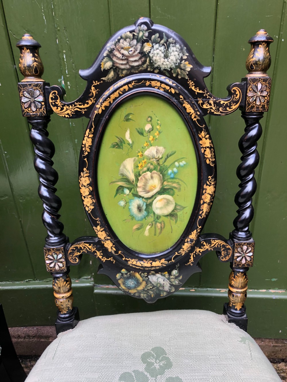 A pair of black lacquered Victorian bedroom chairs featuring oval back panels painted with floral motifs, mother-of-pearl inlay, barley twist legs, and light green upholstered seats. View XV