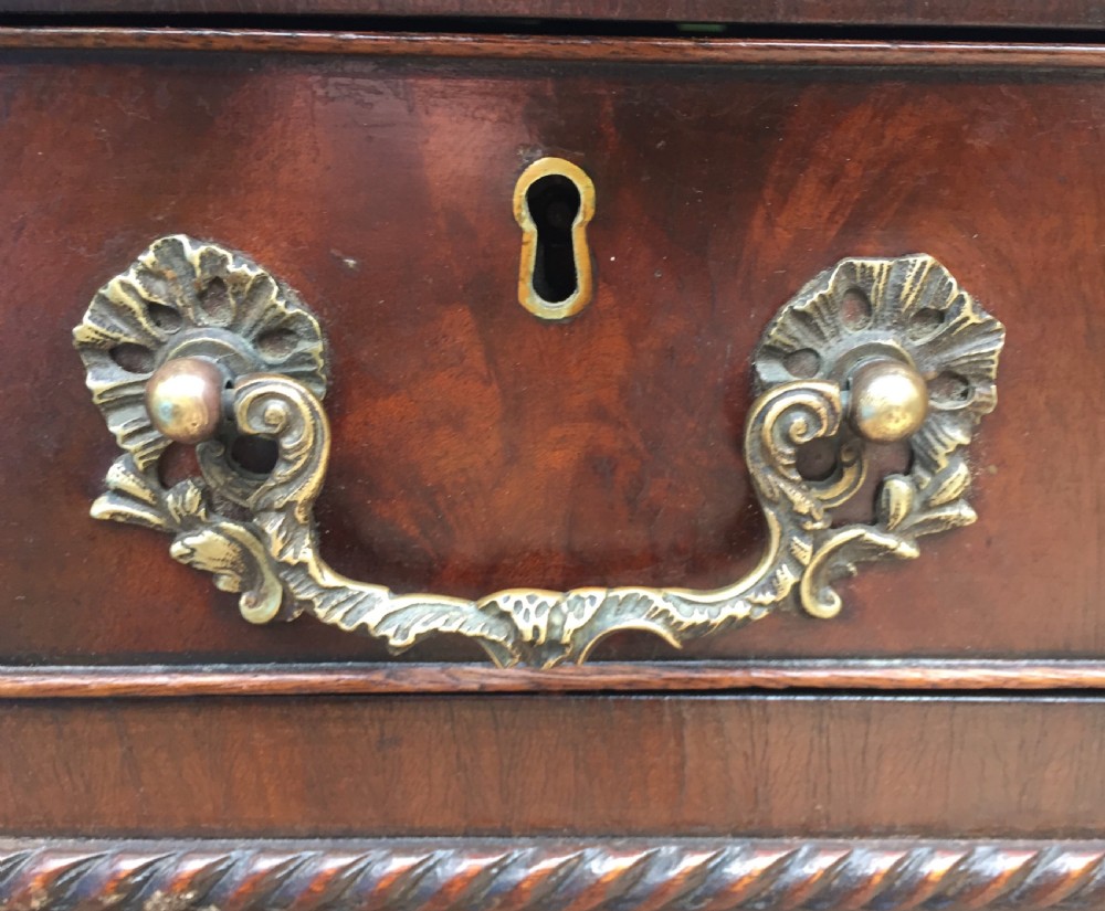 A nineteenth-century Chippendale-revival mahogany partners desk featuring an inset leather top, twin pedestals with drawer storage, brass handles, and carved edge trim. View X