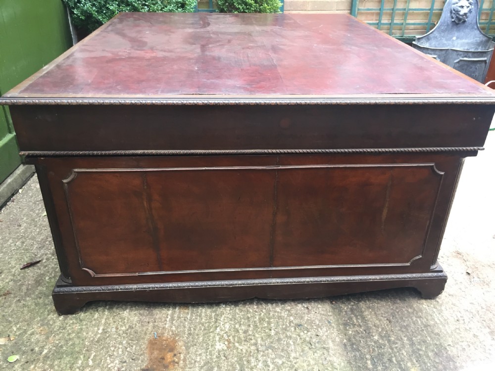 A nineteenth-century Chippendale-revival mahogany partners desk featuring an inset leather top, twin pedestals with drawer storage, brass handles, and carved edge trim. View XII