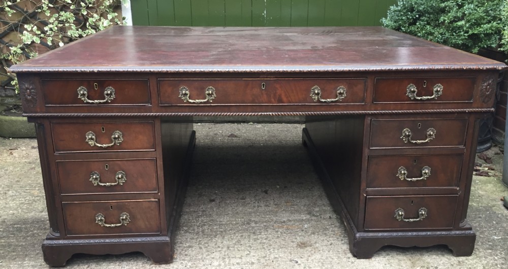 A nineteenth-century Chippendale-revival mahogany partners desk featuring an inset leather top, twin pedestals with drawer storage, brass handles, and carved edge trim. View III
