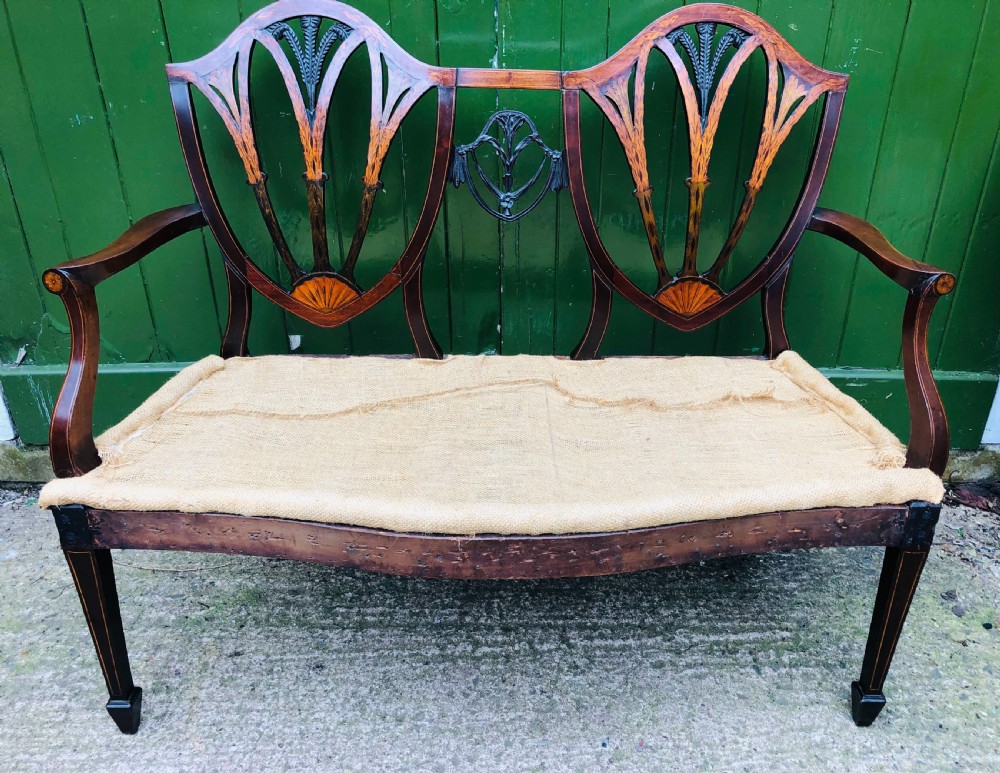 A late nineteenth-century mahogany double chair-back settee featuring shield-shaped backs with satinwood plume inlay and tapered legs. View II