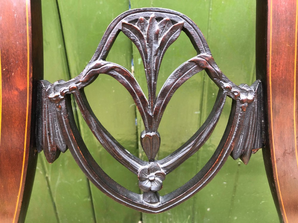 A late nineteenth-century mahogany double chair-back settee featuring shield-shaped backs with satinwood plume inlay and tapered legs. View VI