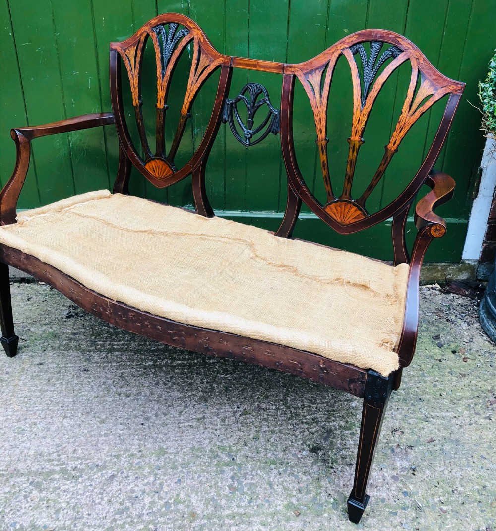 A late nineteenth-century mahogany double chair-back settee featuring shield-shaped backs with satinwood plume inlay and tapered legs. View XIII