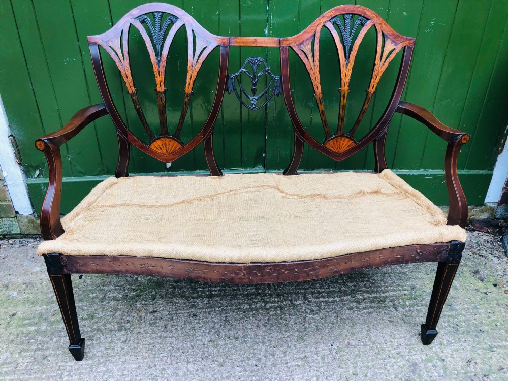 A late nineteenth-century mahogany double chair-back settee featuring shield-shaped backs with satinwood plume inlay and tapered legs. View XV