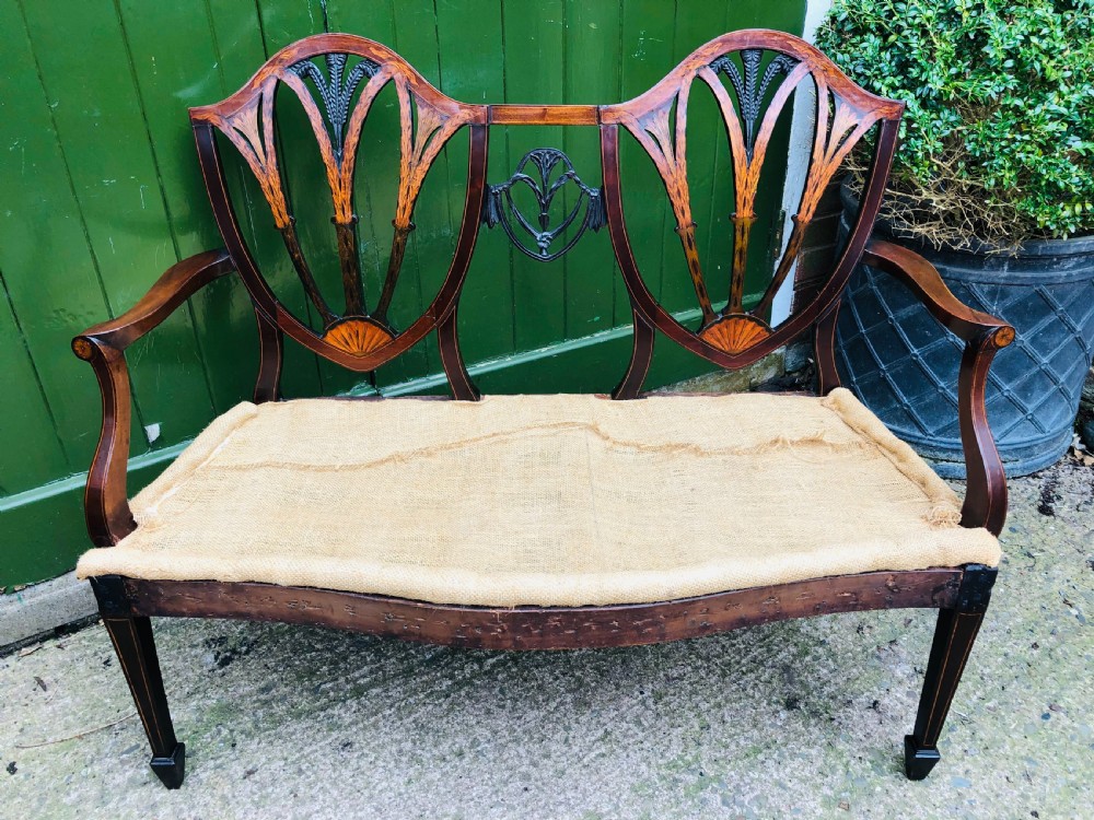 A late nineteenth-century mahogany double chair-back settee featuring shield-shaped backs with satinwood plume inlay and tapered legs. View XVI