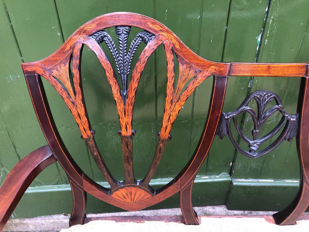 A late nineteenth-century mahogany double chair-back settee featuring shield-shaped backs with satinwood plume inlay and tapered legs. View XVII