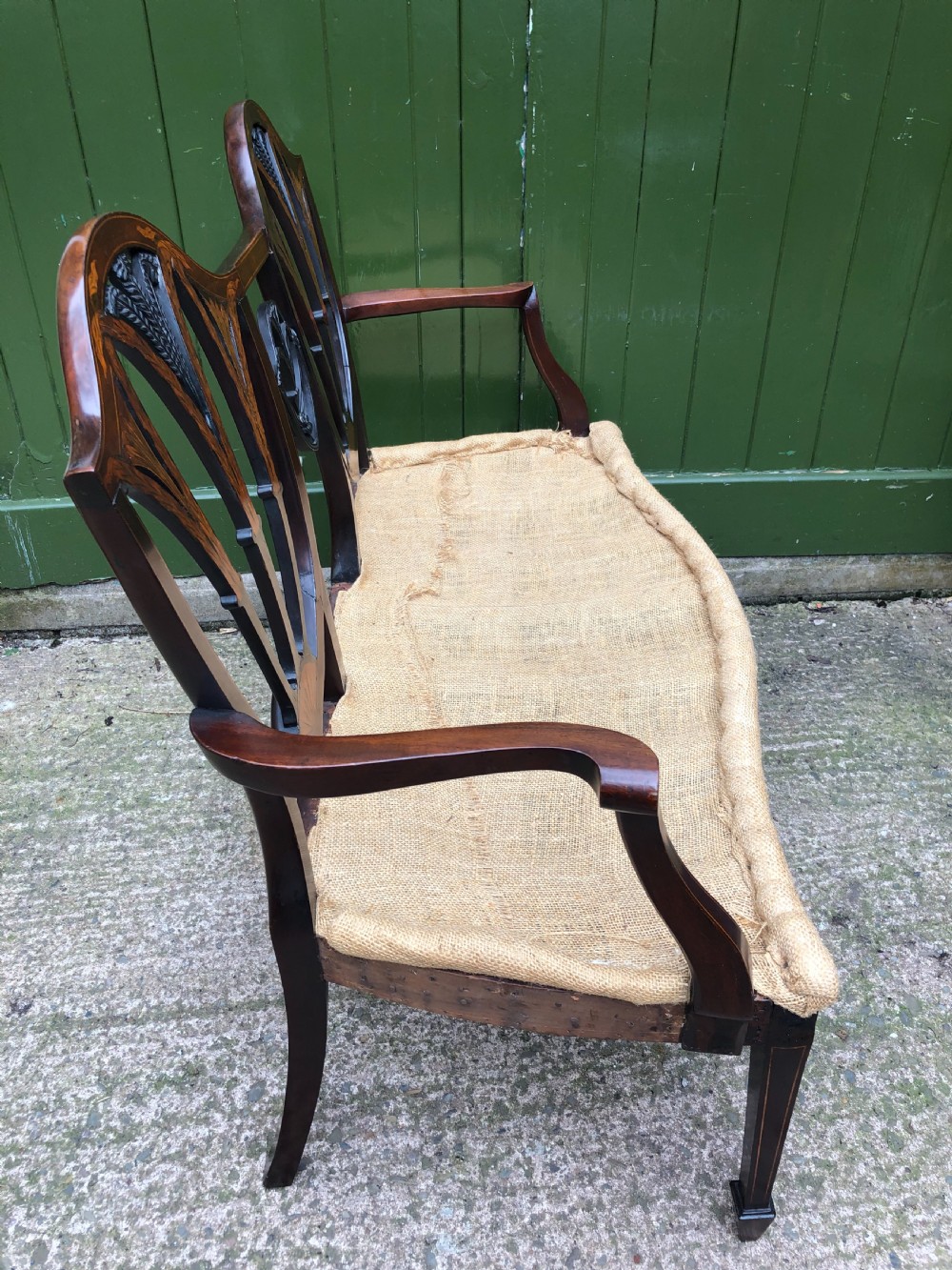 A late nineteenth-century mahogany double chair-back settee featuring shield-shaped backs with satinwood plume inlay and tapered legs. View XVIII