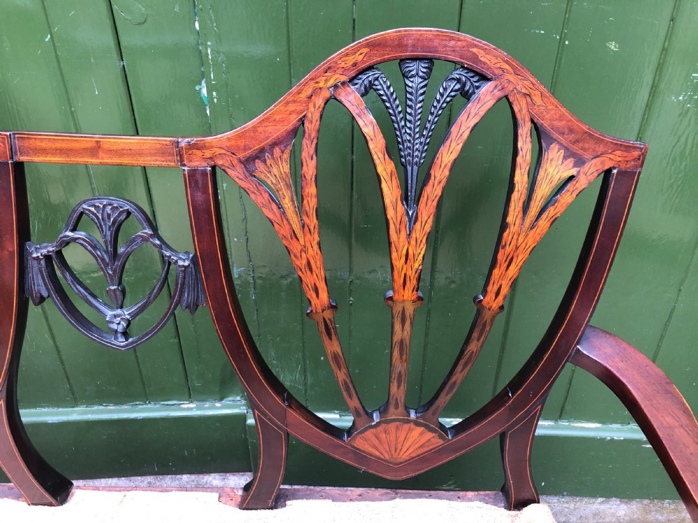 A late nineteenth-century mahogany double chair-back settee featuring shield-shaped backs with satinwood plume inlay and tapered legs. View XIX