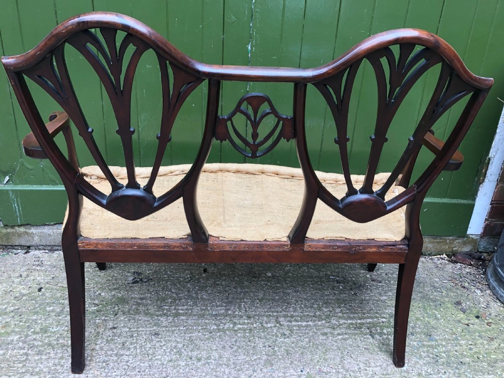 A late nineteenth-century mahogany double chair-back settee featuring shield-shaped backs with satinwood plume inlay and tapered legs. View XX