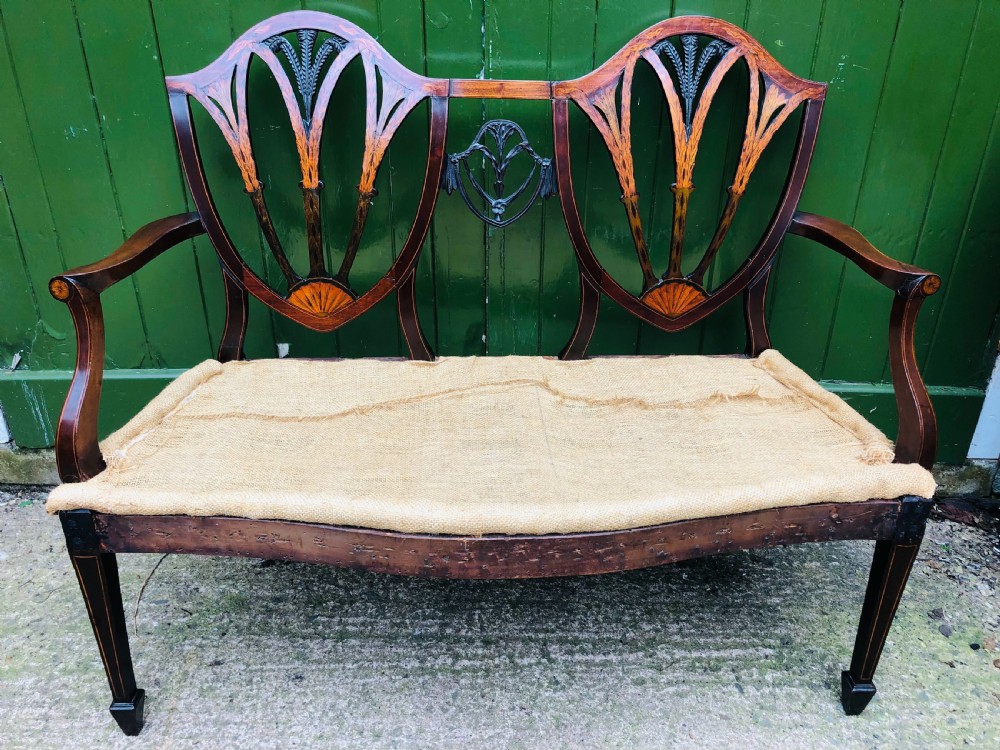 A late nineteenth-century mahogany double chair-back settee featuring shield-shaped backs with satinwood plume inlay and tapered legs. View XXII