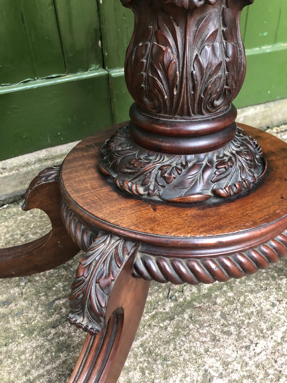 An early 19th-century Regency mahogany fold-over card table featuring carved floral frieze panels, a bulbous carved pedestal stem, and four splayed legs with brass castors. View VII