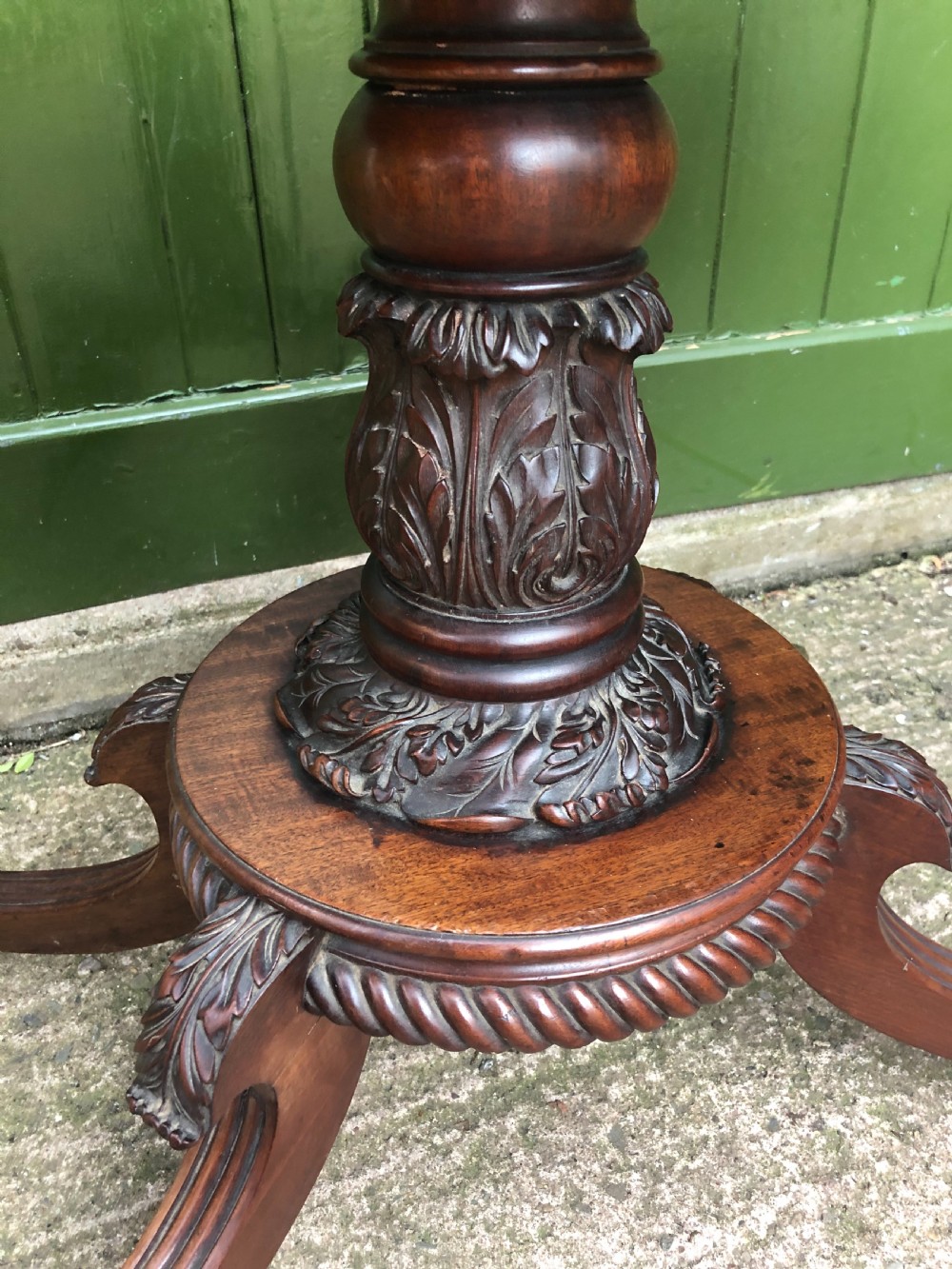 An early 19th-century Regency mahogany fold-over card table featuring carved floral frieze panels, a bulbous carved pedestal stem, and four splayed legs with brass castors. View VIII