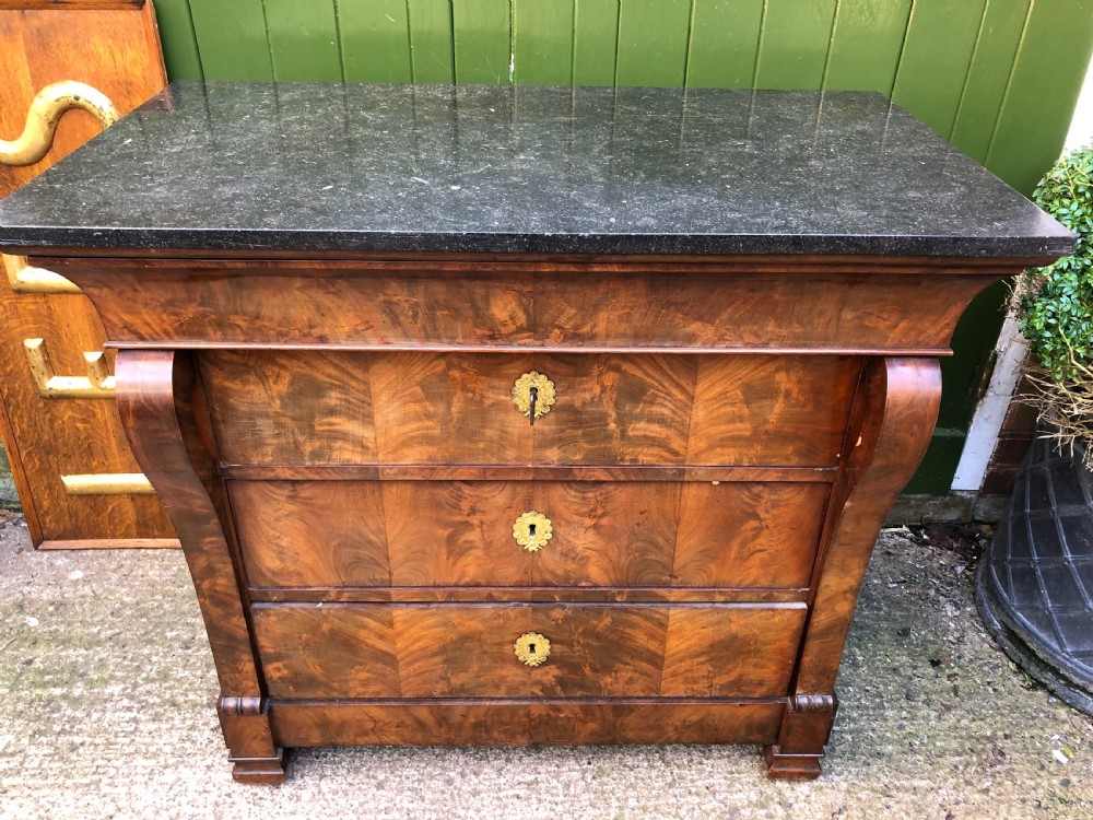 An early nineteenth-century French Empire mahogany commode featuring three drawers with flame mahogany veneer, brass escutcheons, and a thick dark fossil marble top. View II