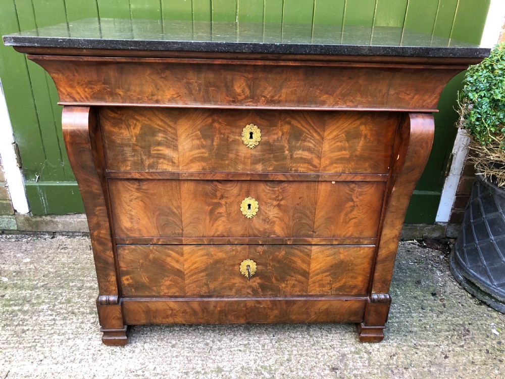 An early nineteenth-century French Empire mahogany commode featuring three drawers with flame mahogany veneer, brass escutcheons, and a thick dark fossil marble top. View IX