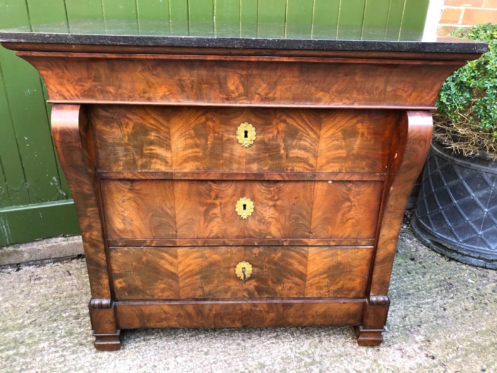 An early nineteenth-century French Empire mahogany commode featuring three drawers with flame mahogany veneer, brass escutcheons, and a thick dark fossil marble top. View XIV