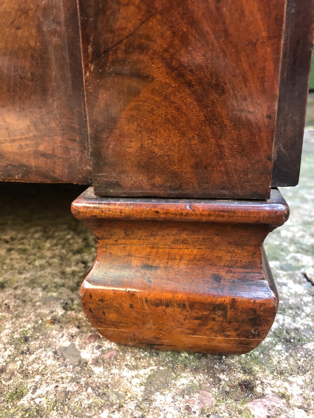 An early nineteenth-century French Empire mahogany commode featuring three drawers with flame mahogany veneer, brass escutcheons, and a thick dark fossil marble top. View XVIII