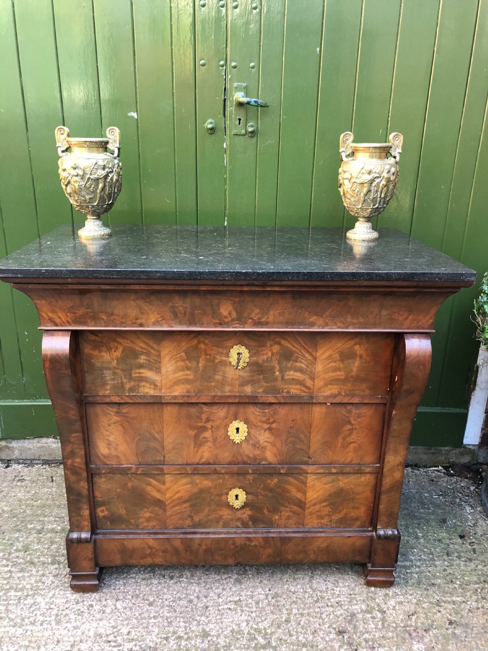 An early nineteenth-century French Empire mahogany commode featuring three drawers with flame mahogany veneer, brass escutcheons, and a thick dark fossil marble top. View XXI